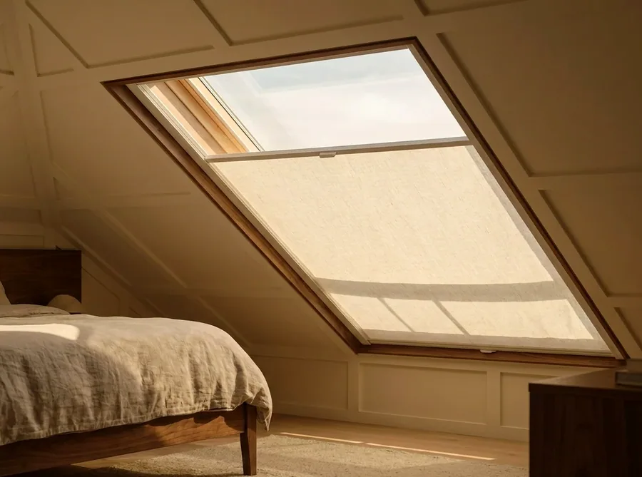 Flat skylight blind running in side channels across an angled roof window in a Parkwood loft conversion